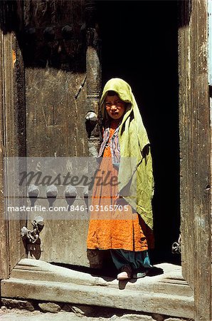LITTLE GIRL STANDING IN THE DOORWAY TYPICAL NEPALESE BRASS-STUDDED