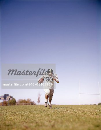 1960s MAN FOOTBALL PLAYER CARRYING BALL RUNNING TOWARDS CAMERA