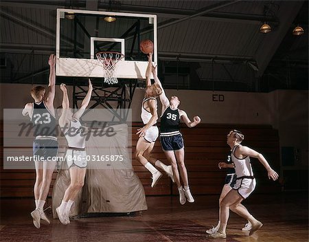 1960s BASKETBALL PLAYERS JUMPING FOR BALL NEAR HOOP HIGH SCHOOL COLLEGE TEAM INTRAMURAL ONE ON ONE