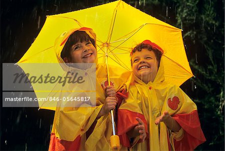 1990s TWO GIRLS WITH UMBRELLA AND YELLOW RAIN SLICKERS