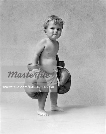 1930s BABY BOY TODDLER WEARING OVERSIZE BOXING GLOVES