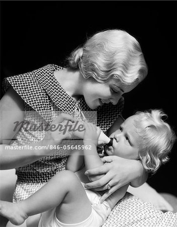 1930s BLONDE WOMAN MOTHER SMILING FEEDING BABY BOTTLE