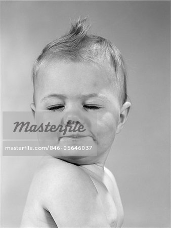 1960s SIDE VIEW OF PORTRAIT BABY WITH CHIN ON SHOULDER & CLOSED EYES SMIRKING TURNING HEAD TOWARD CAMERA