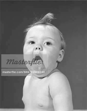 1960s BABY WITH CURL ON TOP OF HEAD & TONGUE STICKING OUT