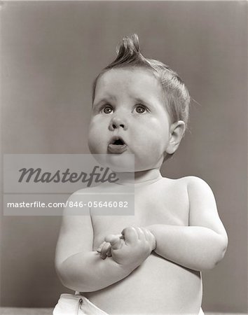 1950s WORRIED BABY LOOKING UP UNCERTAIN WITH CLASPED HANDS STUDIO