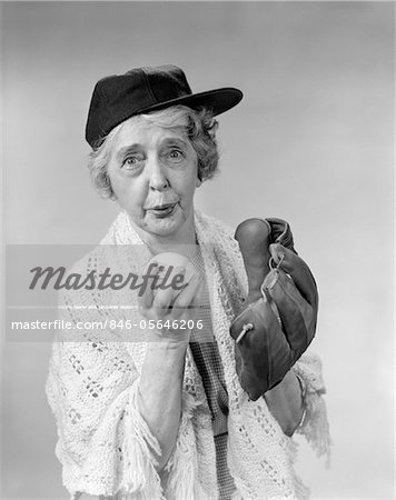 1950s - 1960s GRANNY WEARING BASEBALL HAT & GLOVE ABOUT TO PITCH BALL LOOKING AT CAMERA