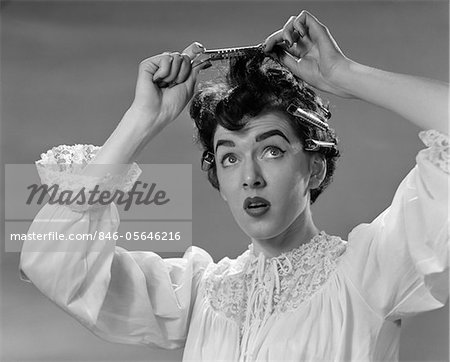 1950s WOMAN IN NIGHTGOWN PUTTING ROLLER CLIPS IN HAIR