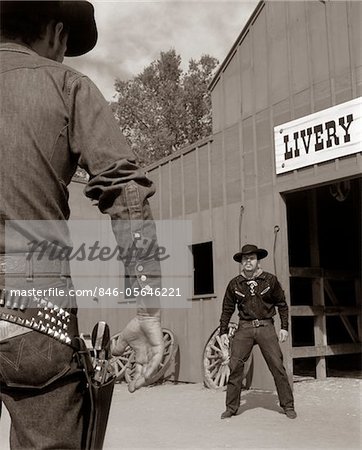 1950s - 1960s TV COWBOYS IN FRONT OF LIVERY STABLE READY TO DRAW PISTOLS IN GUNFIGHT