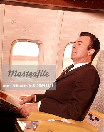1960s MAN SITTING IN FIRST CLASS AIRPLANE PASSENGER SEAT