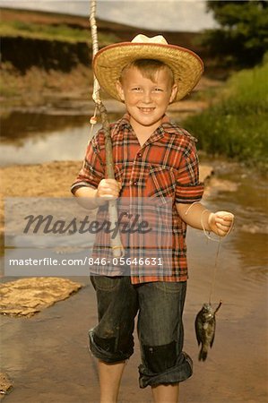 1950s SMILING BOY STRAW HAT HOLDING FISHING POLE WEARING PLAID SHIRT BLUE JEANS