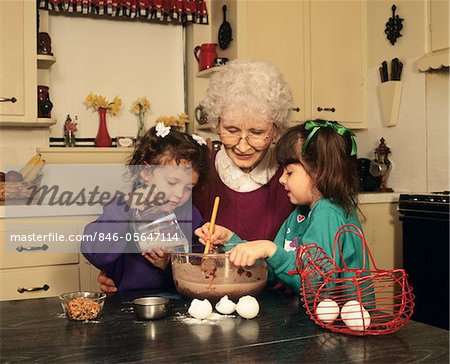 GRANDMOTHER WITH GRANDDAUGHTERS COOKING IN KITCHEN