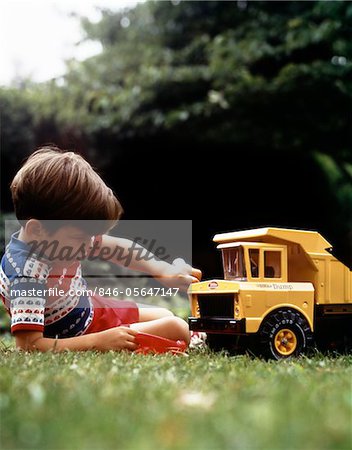 1970s BOY IN GRASS PLAYING WITH TONKA TOY YELLOW DUMP TRUCK