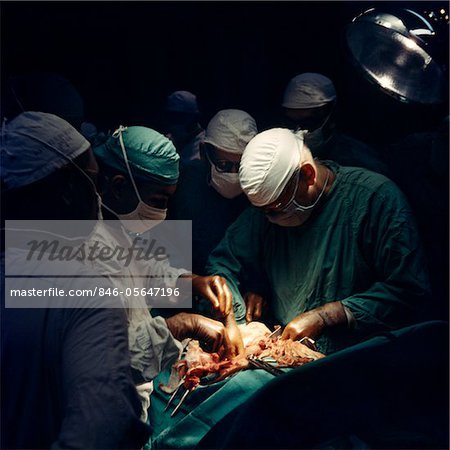 1960s DOCTORS AND NURSES IN SURGERY OPERATING THEATER PERFORMING MEDICAL PROCEDURE