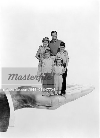1960s SYMBOLIC PORTRAIT OF FAMILY FATHER SON MOTHER DAUGHTER HELD STANDING TOGETHER IN PALM OF HAND
