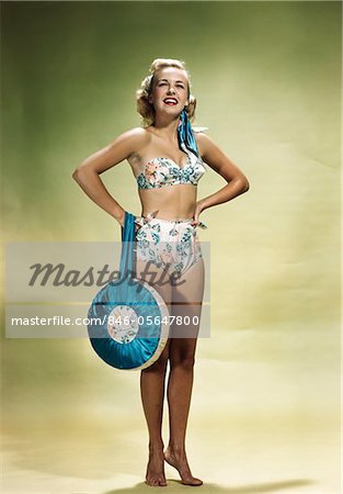 1950s SMILING WOMAN WEARING TWO PIECE FLORAL BIKINI HOLDING