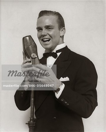 1920s - 1930s SMILING MAN RADIO SINGER ENTERTAINER CROONER IN TUXEDO SINGING INTO MICROPHONE