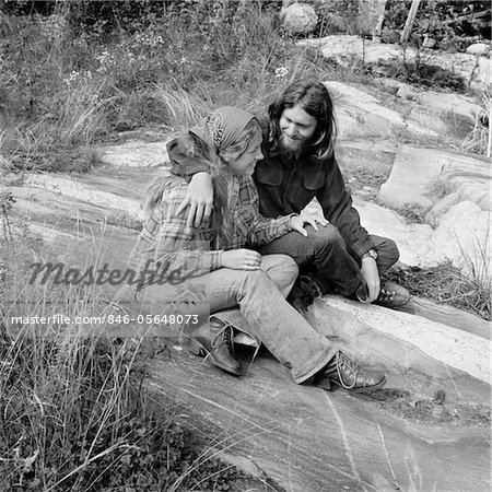 1960s - 1970s ROMANTIC YOUNG HIPPIE COUPLE SITTING OUTDOORS