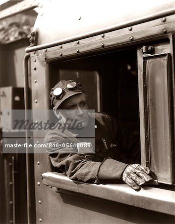 1920s - 1930s - 1940s RAILROAD TRAIN ENGINEER LOOKING OUT WINDOW OF LOCOMOTIVE CAB DRIVING THE STEAM ENGINE