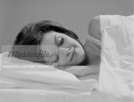 1960s BRUNETTE WOMAN IN BED SLEEPING SMILE ON HER FACE