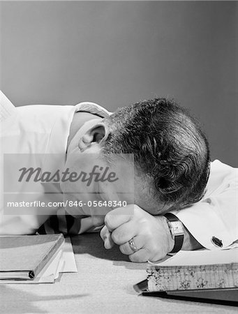 1950s MAN WITH HEAD ON DESK IN FRUSTRATION EXHAUSTION