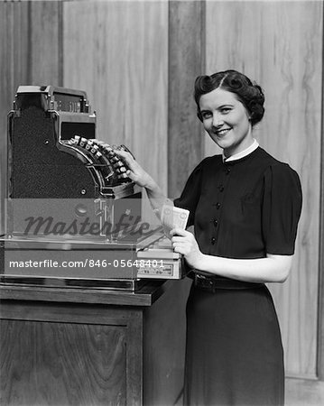 1930s SMILING SALES WOMAN RINGING UP SALE ON CASH REGISTER