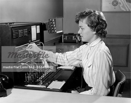 1950s WOMAN OFFICE TELEPHONE SWITCHBOARD RECEPTIONIST OPERATOR WEARING HEADSET ANSWERING TRANSFERRING CALL
