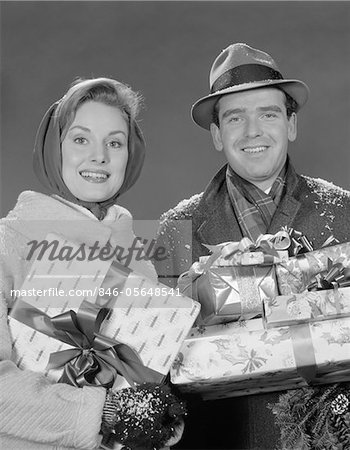 1960s COUPLE MAN AND WOMAN HOLDING WRAPPED CHRISTMAS PRESENTS AND PACKAGES