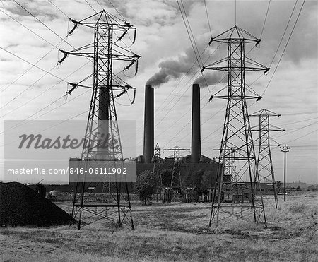 1950s INDUSTRIAL POWER PLANT BILLOWING SMOKE TO GENERATE ELECTRICITY POWER LINE TOWERS IN FOREGROUND