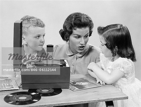 1950s MOTHER DAUGHTER & SON LISTENING TO 45'S ON PORTABLE RECORD PLAYER 1950s MOTHER DAUGHTER & SON LISTENING TO 45'S ON PORTABLE RECORD PLAYER