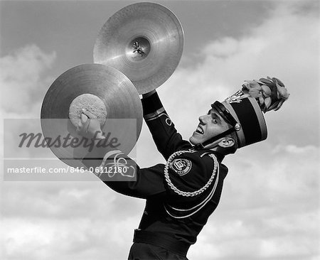 1960s PORTRAIT OF BOY IN BAND UNIFORM PLAYING INSTRUMENT CYMBALS OUTDOORS