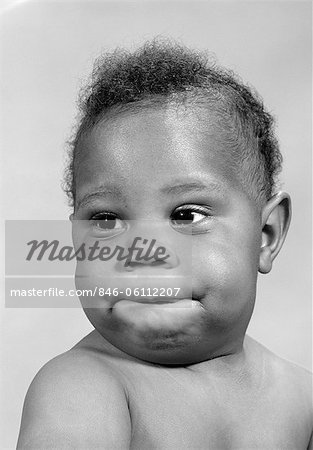 1960s PORTRAIT OF AFRICAN-AMERICAN BABY MAKING A FUNNY FACE BITING HIS LIP