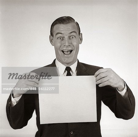 1950s 1960s EXCITED BUSINESSMAN LOOKING AT CAMERA HOLDING BLANK WHITE CARD