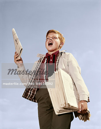 1960s PAPERBOY WITH STACK NEWSPAPERS UNDER HIS ARM SHOUTING EXTRA EXTRA
