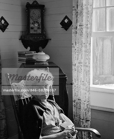 Elderly woman sadly looking out the window, a black-and-white ph