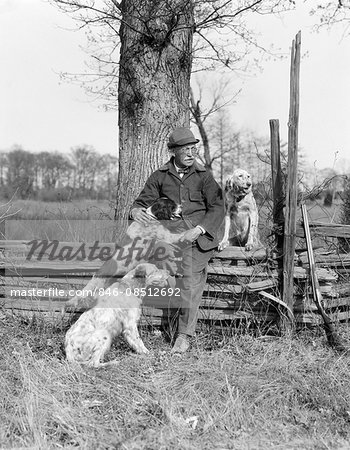 1920s 1930s SENIOR MAN HUNTING CLOTHES SITTING SPIT RAIL FENCE WITH THREE ENGLISH SETTER DOGS
