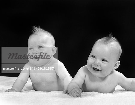 1950s TWO TWIN BABIES SMILING LYING ON THEIR STOMACHS LOOKING UP