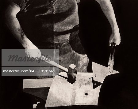 1935s CLOSE-UP ANONYMOUS SILHOUETTED BLACKSMITH HANDS WORKING METAL ON ANVIL WITH HAMMER