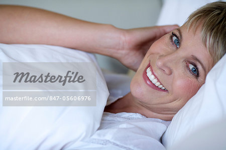 Mature Short Haired Woman Relaxing In Bed Stock Photo