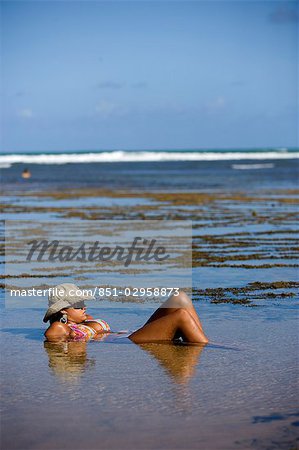 Woman lying partially submerged in rockpool,Praia do Forte,Bahia,Brazil