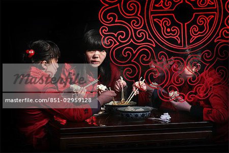 Chinese girls eating with chopsticks in Pingyao,a UNESCO World Heritage Site,Shanxi,China
