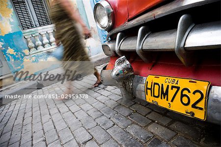 Woman passing old American yank tank,Havana,Cuba