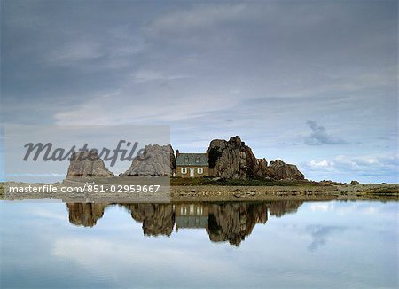 House in between rocks reflected,Brittany,France.