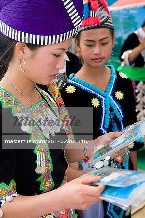 Hmong girls in traditional costume looking at photos of themselves at the New Year festival,Phonsavan,Laos