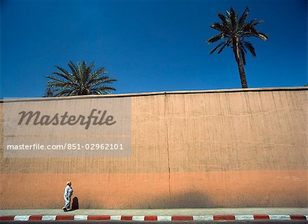 woman walking on street next to wall,Marrakesh,Morocco