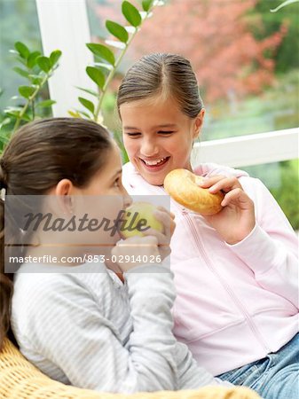 Two girls eating in armchair Two girls eating in armchair