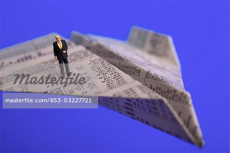 High angle view of figurine of businessman standing on paper airplane