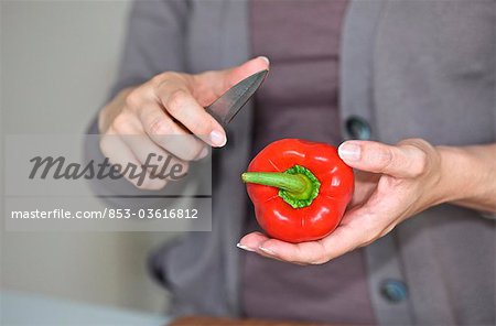 Woman slicing pepper in kitchen, close-up