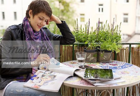 Young woman reading magazine on balcony