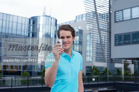 Young man with smartphone in front of office building