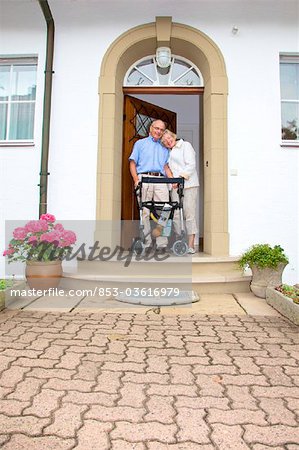 Senior couple with walking frame at the front door